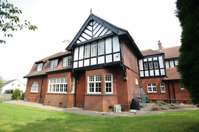 color photo of large red brick faux Tudor house.